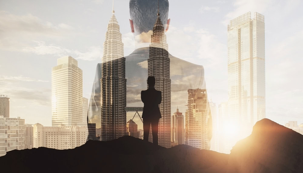 businessman standing and looking over the city while the sun sets