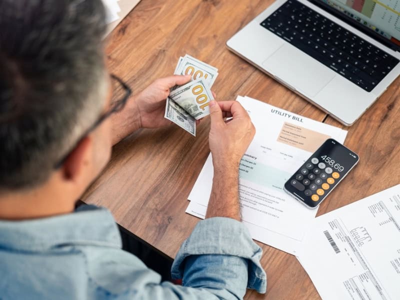 man calculating expenses with laptop and calculator
