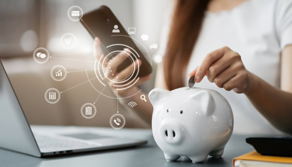 person dropping savings on piggy bank